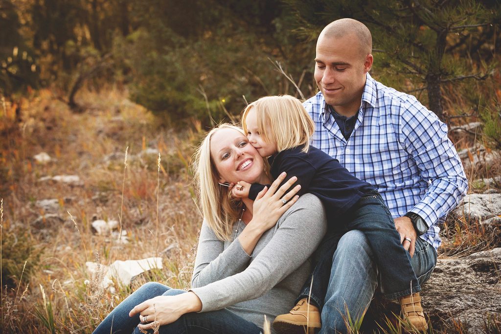 Rapid City, South Dakota family photography, mom and dad with little boy, boy kissing mom in a rugged woodsy area